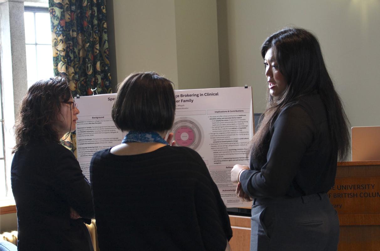 Laurie He pictured on the right, presenting her research poster to people standing on her left