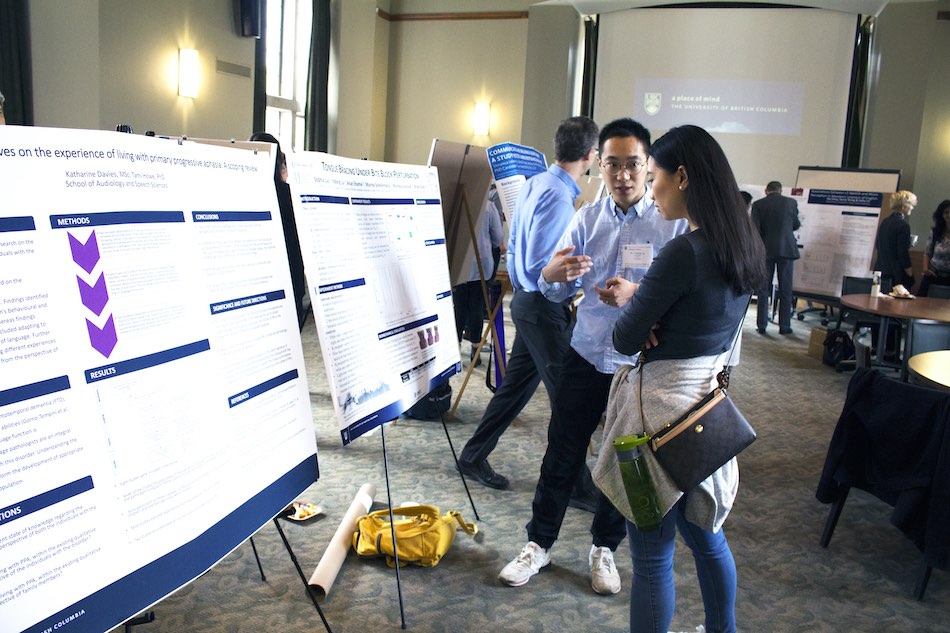 Two students standing in front of research posters in a room, in a discussion