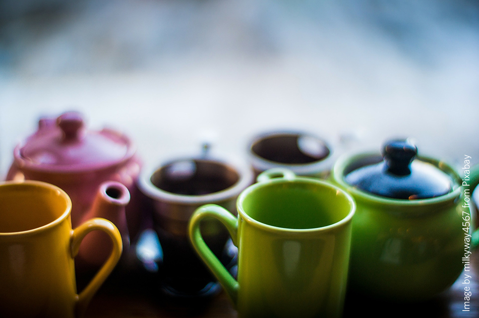 A close up of different coloured mugs and teapots