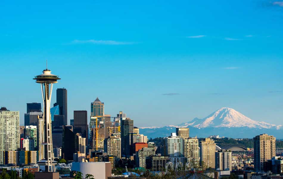 A photo of the Seattle skyline with blue sky and a mountain in the background