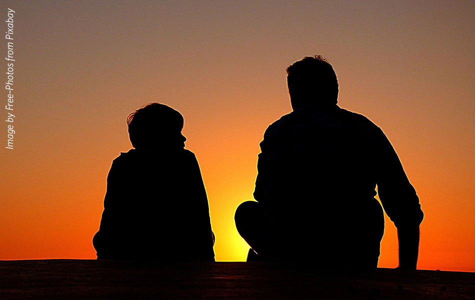 Silhouettes of an older man and child against the setting sun