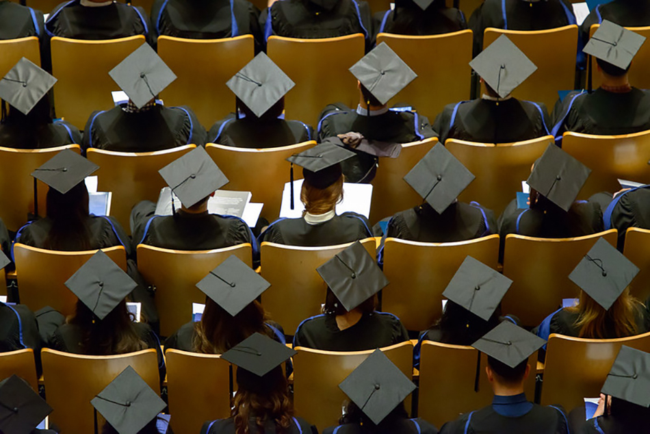 An eagle eye picture of UBC graduates sitting in rows facing forwards and wearing their graduation caps.