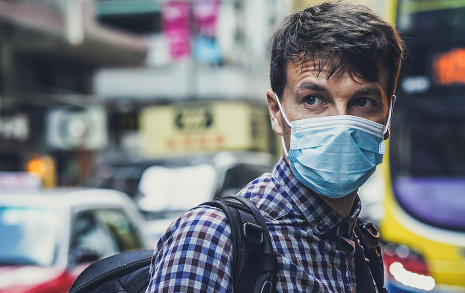 An image of a man wearing a surgical mask in a busy street