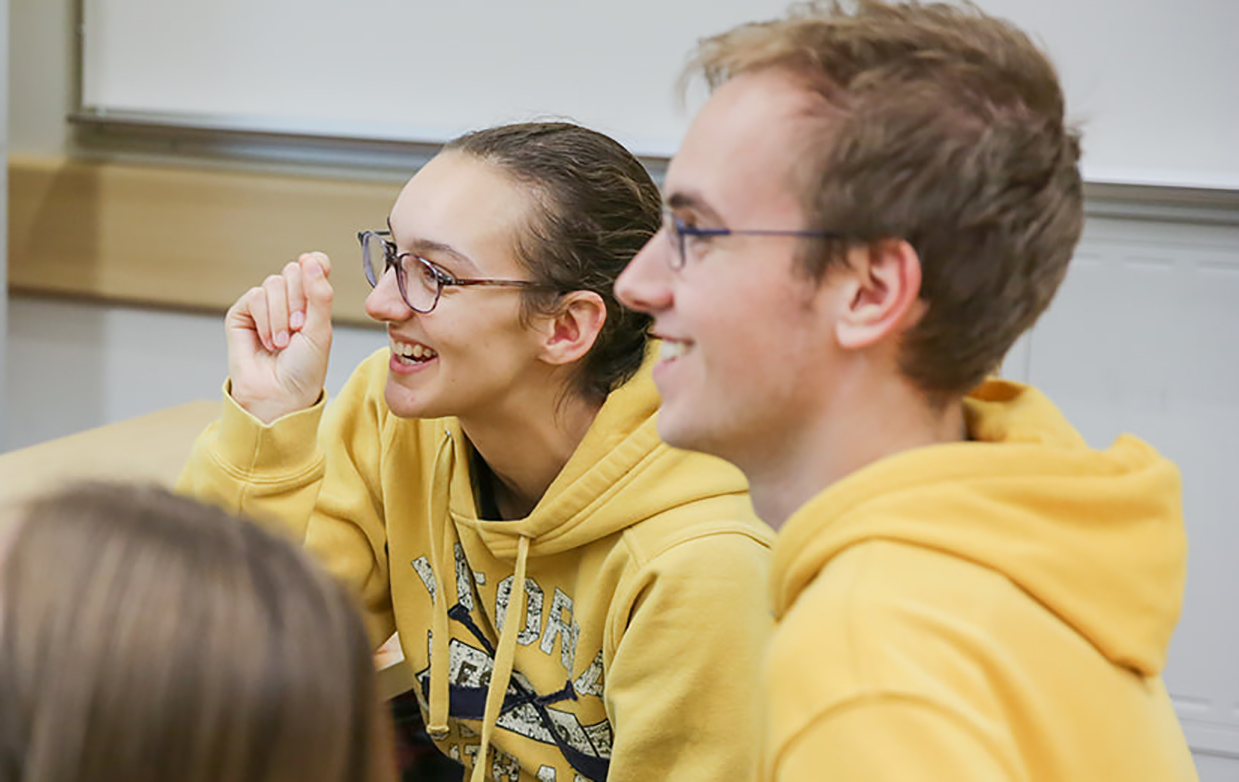 An image of Paris and Kelton, both wearing yellow jumpers, laughing in class