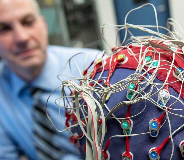 An image of Tony Herdman looking at a person wearing an EEG cap