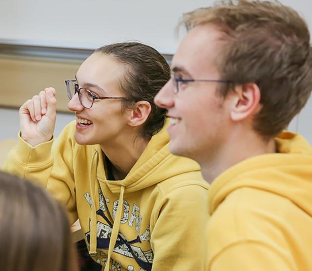 An image of Paris and Kelton, both wearing yellow jumpers, laughing in class