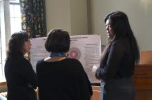 Laurie He pictured on the right, presenting her research poster to people standing on her left
