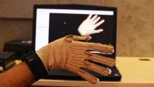 An image of the Cyberglove used to generate sound from movements, placed in front of a computer showing a 3D graphic of a hand