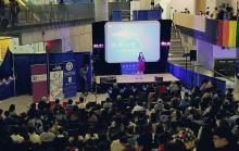 A picture of Zoe Lam onstage at a Cantonese languagae program event in a mall, in front of a crowd of people