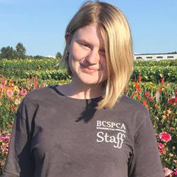 A headshot of Nicole Ebbutt standing in front of a field of flowers